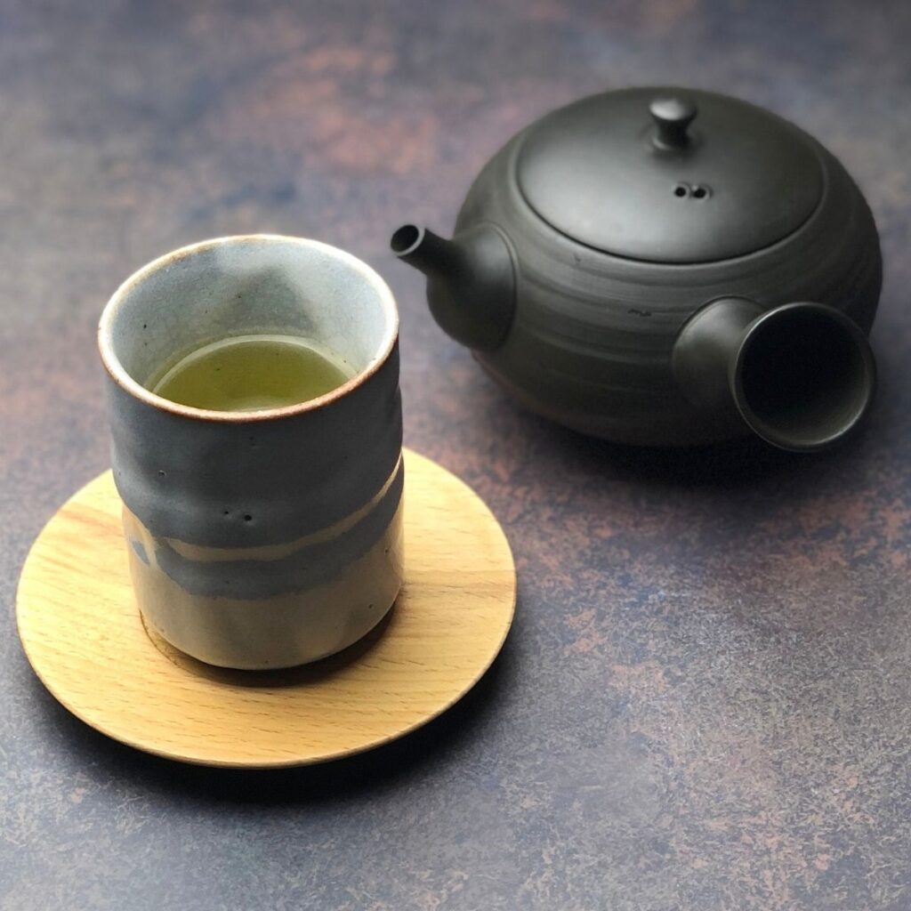 A Japanese teapot and cup placed on a wooden table in soft natural light.